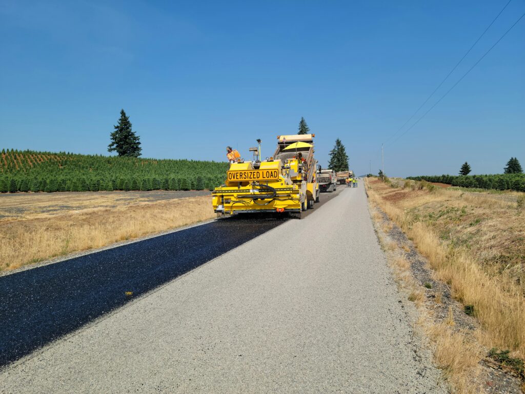 Road construction in rural Sublimity, Oregon with heavy machinery on a sunny day.